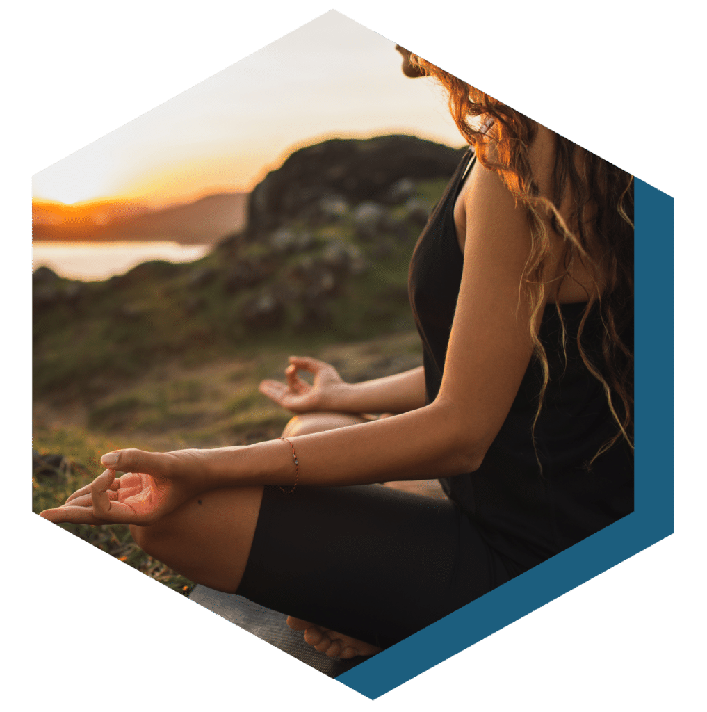 Woman in recovery siting outside in the mountains during sunset doing a meditation